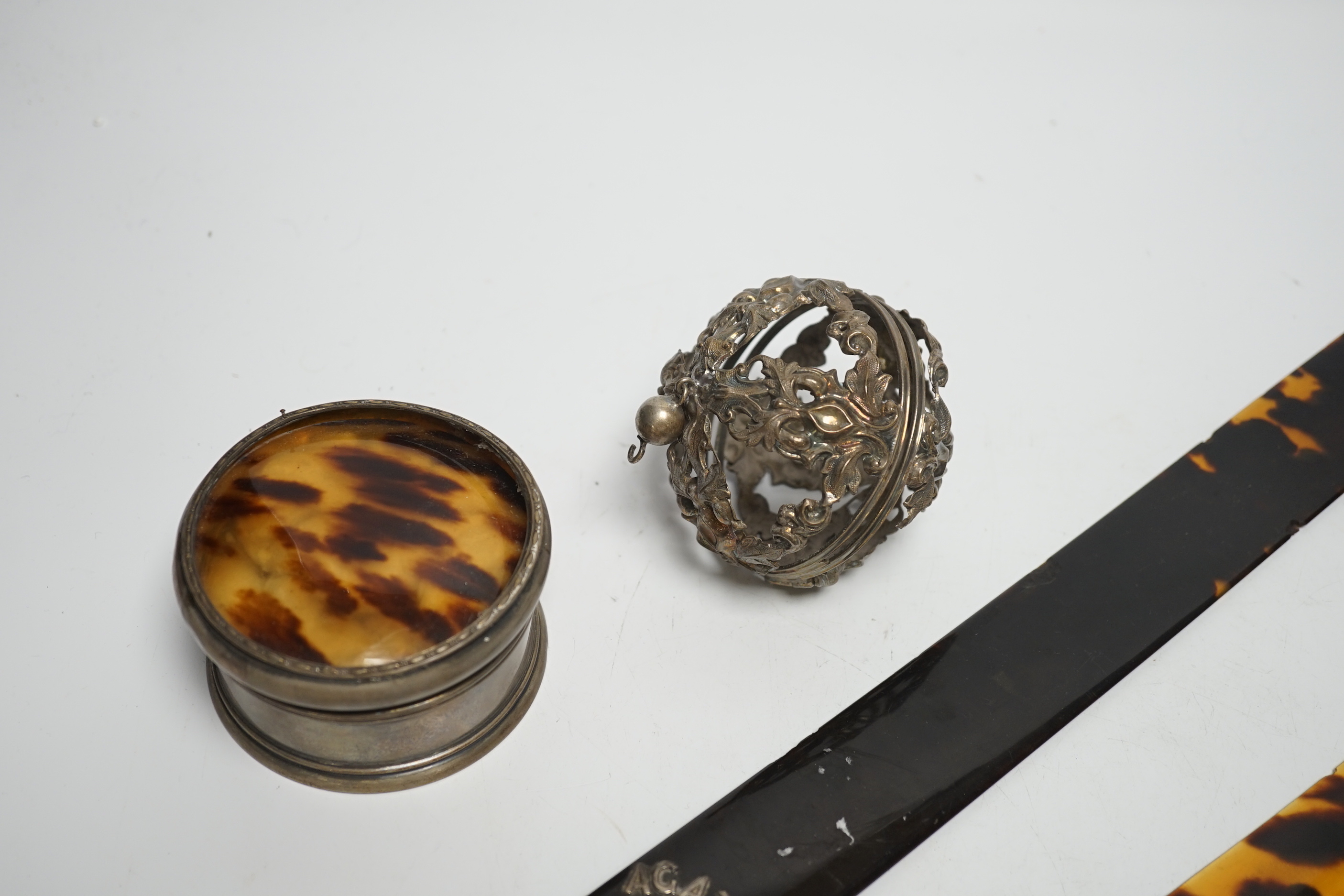 A late Victorian silver handled tortoiseshell page turner, a small page turner, a silver and tortoiseshell box and brush and a white metal pomander case.